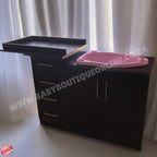 Black cabinet with pink tray against a white curtain background