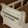 White cot holder with 'Cot Holder' text on a brown background
