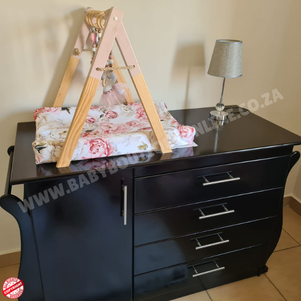 Black dresser with a wooden baby play gym and lamp on top