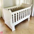 3-in-1 Sleigh Cot and Co-Sleeper White baby crib on a wooden floor with white curtains in the background