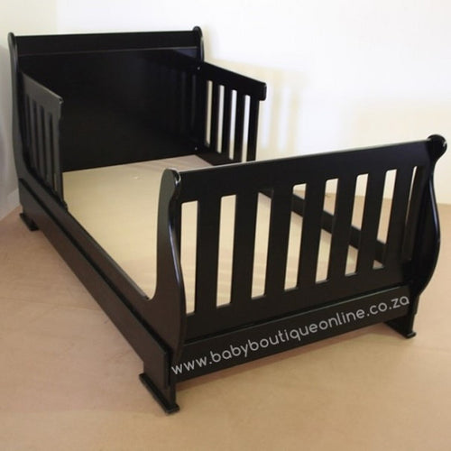 Black toddler bed on a beige floor with a white background
