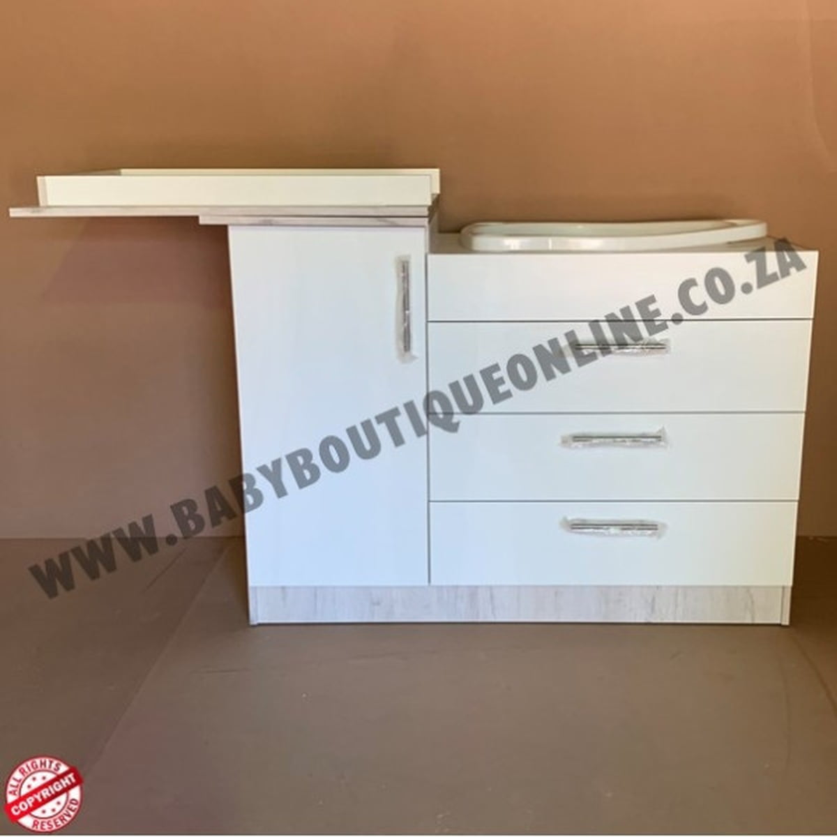 White vanity unit with drawers against a brown background, featuring 'www.babyboutiqueonline.co.za' text.