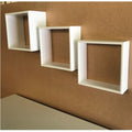 Three white square shelves on a brown wall