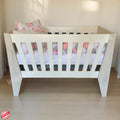 Emma Large Wooden Cot-White_NordicIce White crib with floral bedding on a wooden floor