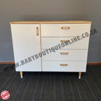 White dresser with gold handles on a gray floor and wall.
