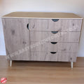 Wooden dresser with three drawers on a wooden floor against a white wall.
