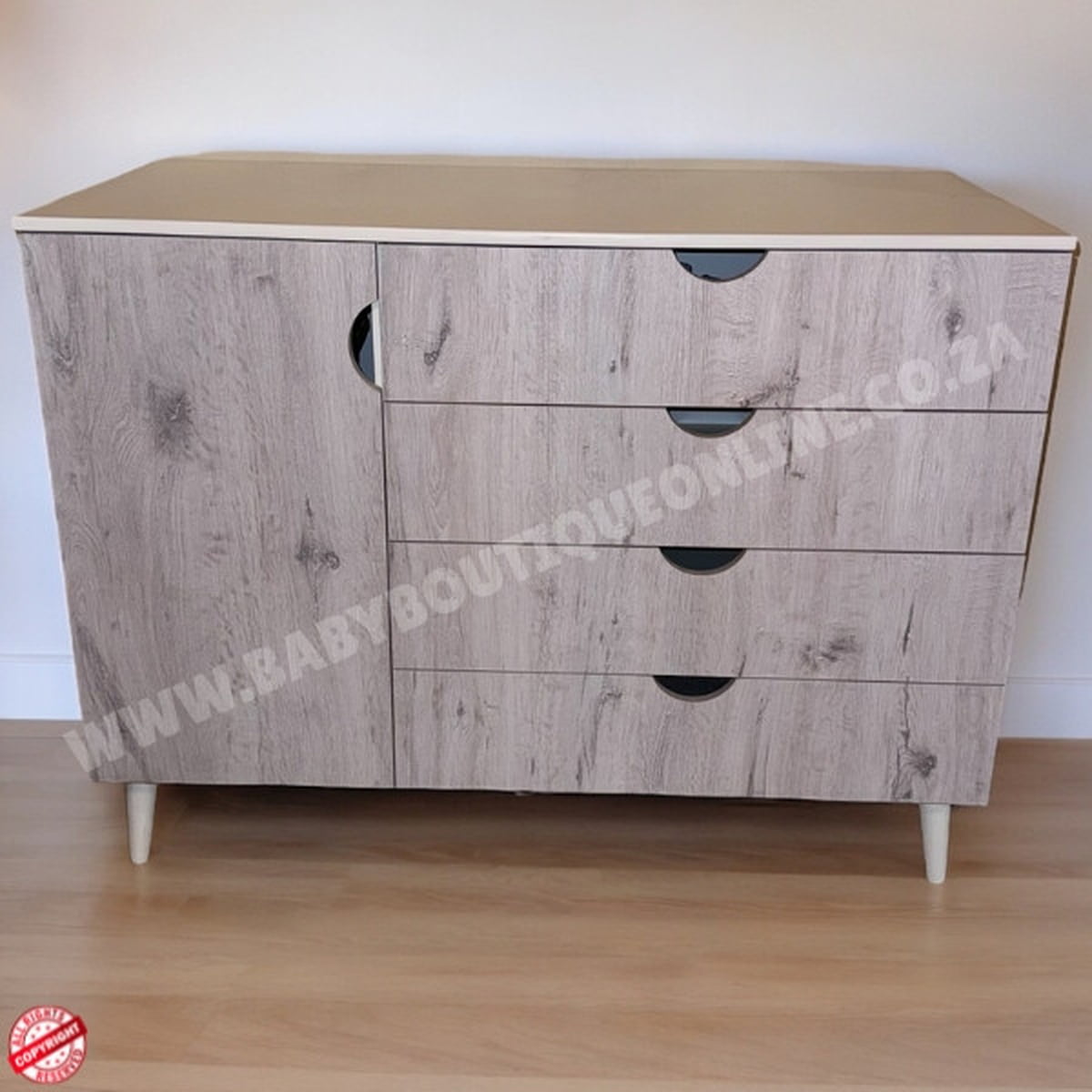 Wooden dresser with three drawers on a wooden floor against a white wall.