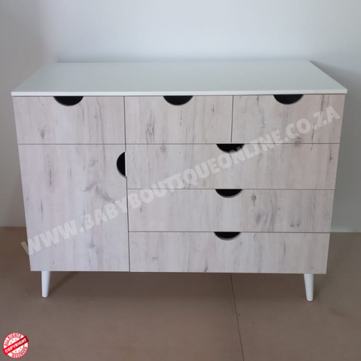 Wooden dresser with white top and black handles on a plain background
