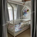 Children's room with a white crib and colorful bedding, curtains, and ceiling fan.