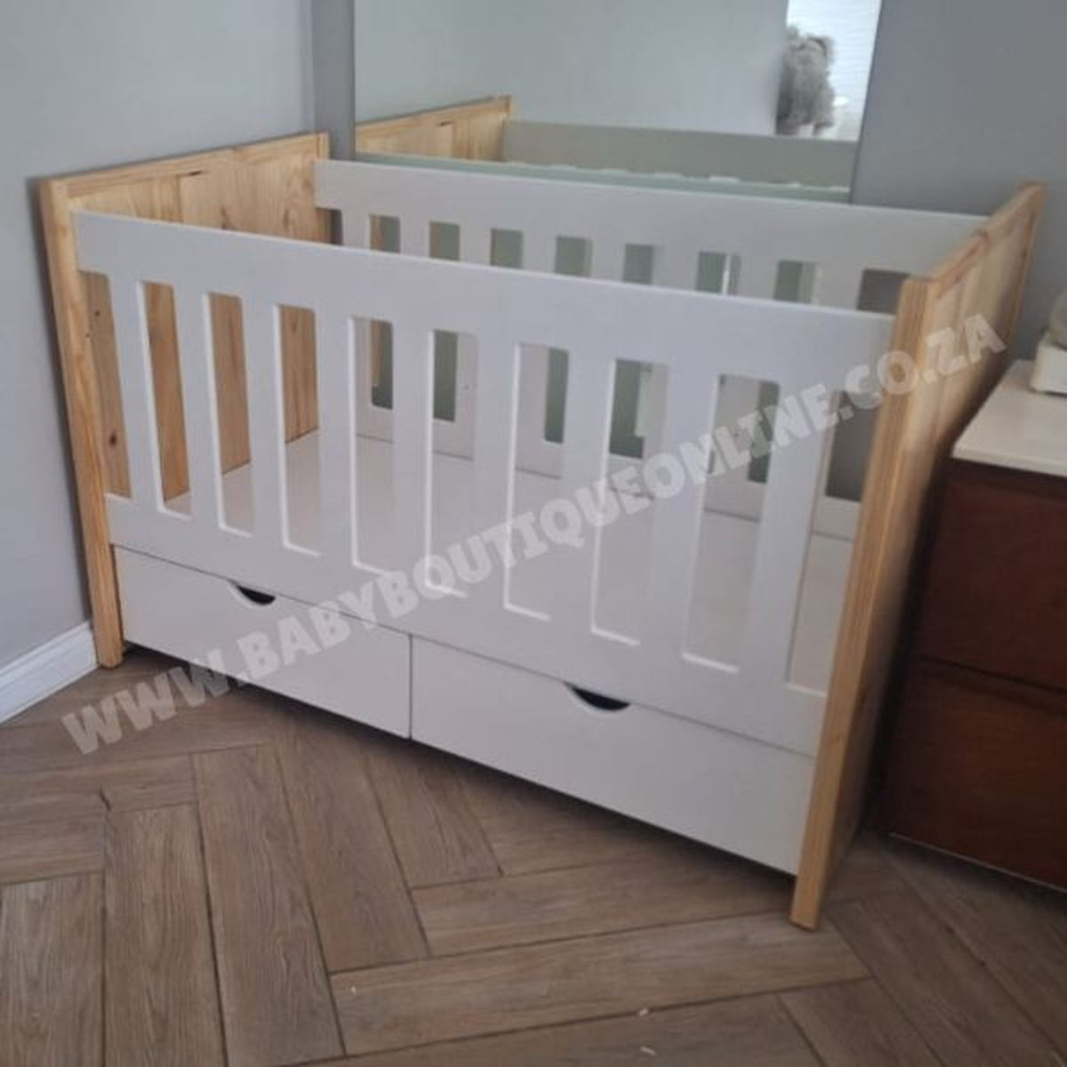 Large Cot-Pine White crib with wooden sides in a room with a wooden floor and dresser.