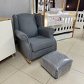 Gray armchair with matching ottoman on a tiled floor in a store setting.