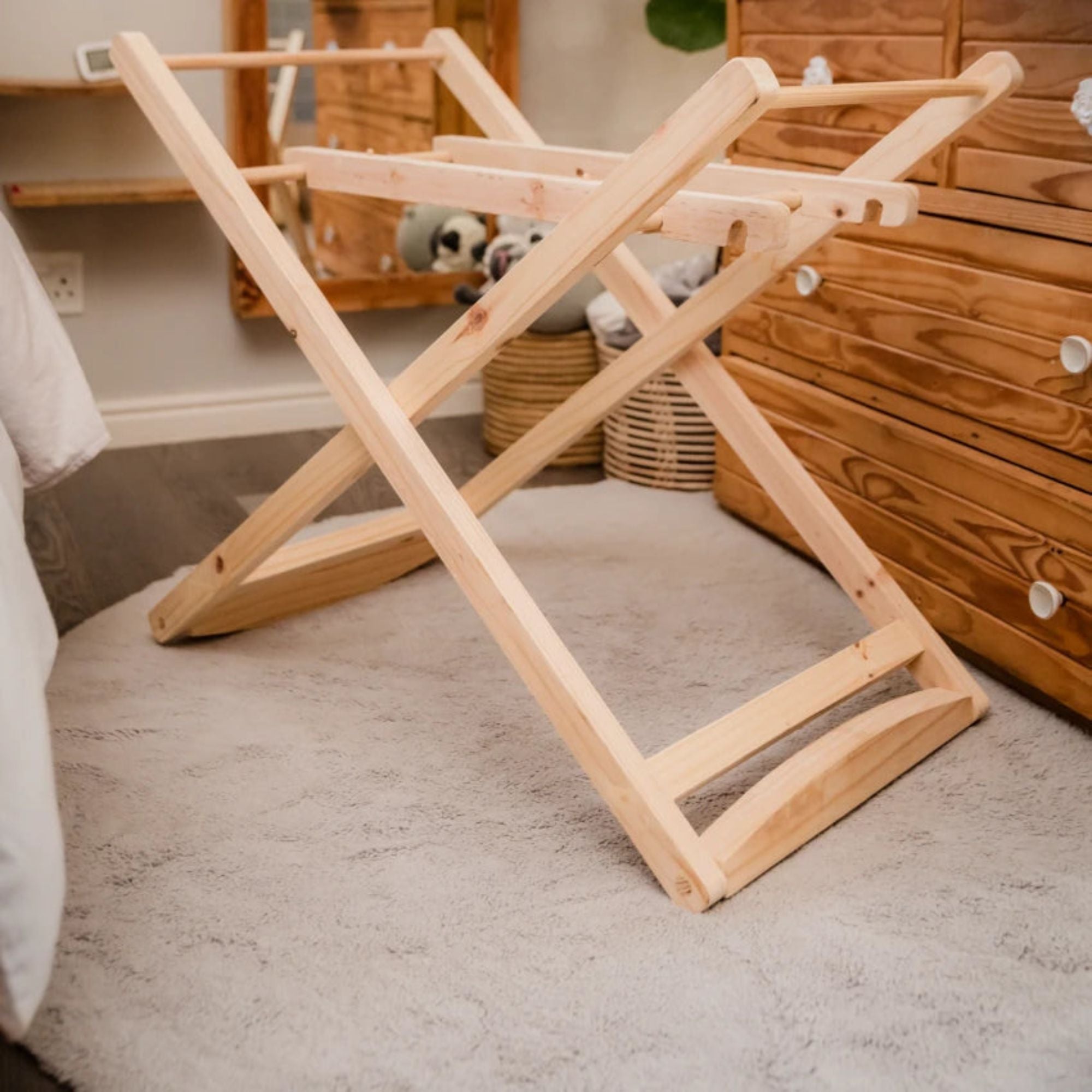 Wooden folding laundry rack on a carpeted floor with wooden furniture in the background